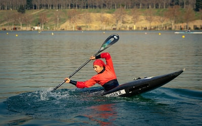 在红色和黑色夹克骑在黑色kayak的水域在白天
